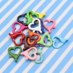 Macro shot of colorful heart-shaped lobster clasps on a striped fabric background