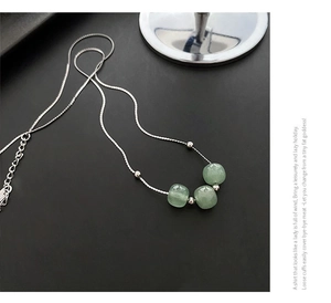 Detail of three light green jade beads on a polished silver chain necklace for women
