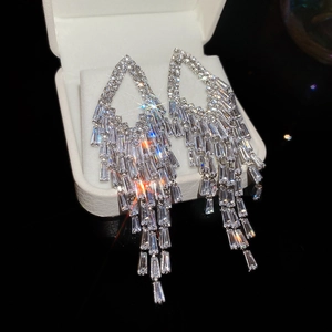 Detailed view of silver-tone tassel earrings with geometric crystals on a white box