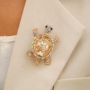 Broche tortue dorée élégante avec cristaux sur le revers d'un blazer beige chic