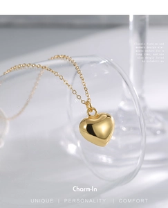 Detail of 3D gold heart pendant necklace draped on transparent glass with minimalist background