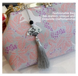 Close-up of retro folding fan charm with ink bamboo pattern and long silver silk tassel