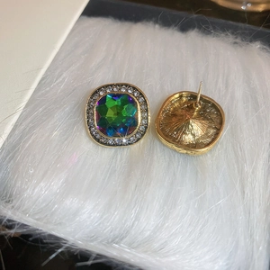 Gros plan de puces d'oreilles carrées vert émeraude avec halo de diamants et or