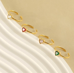 Detail of adjustable gold heart rings with colorful crystals on white wavy pedestals