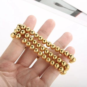 Detailed view of triple-layered gold bead stretch bracelets with high polish finish