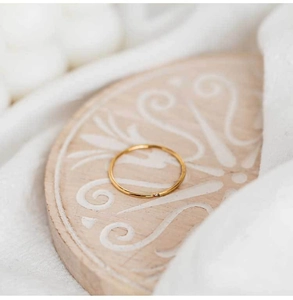 Macro detail of slim gold ring with single zircon stone on vintage carved wood