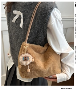 Brown faux fur tote bag with plush charm accessory shown in a casual shoulder carry pose