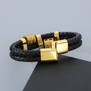 Détail d'un bracelet multicouche en cuir tressé noir avec fermoir magnétique doré pour homme