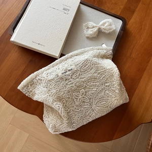 Detail of floral lace makeup bag with matching bow on a rustic wooden tray table