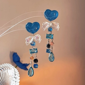 Detail of long tassel earrings featuring blue resin hearts and butterfly bow accents