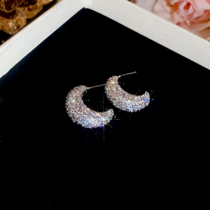 Macro shot of silver crescent earrings with pave-set zircons on black velvet padding