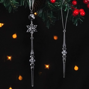 Transparent crystal snowflake and icicle ornaments hanging on a Christmas tree branch