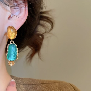 Nahaufnahme von Vintage-Harzohrringen mit Goldrahmen, getragen von einem Modell