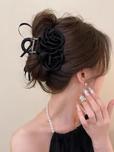Detail of elegant black fabric double rose hair claw clip worn on a low bun hairstyle