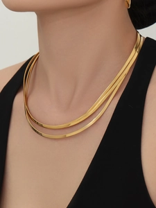 Détail d'un collier à trois couches en maille serpent dorée avec une finition miroir poli