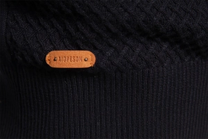 Macro detail of men's knit sweater featuring waffle texture and embossed leather brand tag