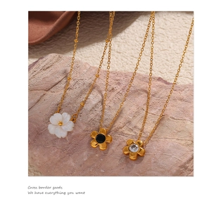 Detailed shot of three minimalist daisy necklaces on stone with gold metal chains