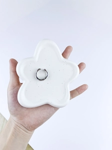 Detailed close-up of a silver irregular open ring displayed on a star ceramic tray