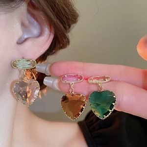Detail of heart-shaped crystal earrings in purple, amber, and emerald with gold trim
