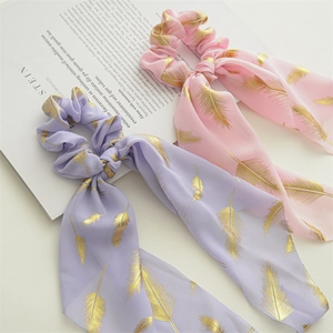 Detail of pink and purple floral chiffon hair scrunchies with gold feather patterns