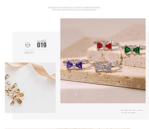 Detail of a bow-shaped ring featuring colorful gemstones and a polished silver finish