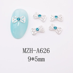 Macro detail of 9x5mm silver bow nail charms with blue rhinestones for art decoration