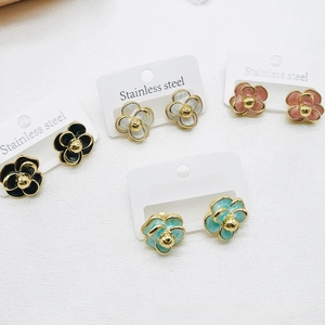 Detailed macro view of camellia flower earrings in black, white, pink and blue shades