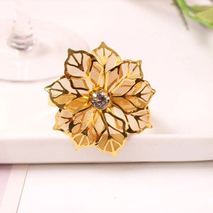 Detail of golden napkin ring featuring a hollow leaf design and central rhinestone