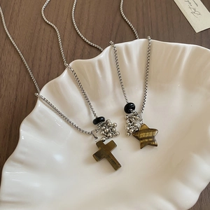 Close-up of tiger eye stone cross and star pendants on silver box chain necklaces