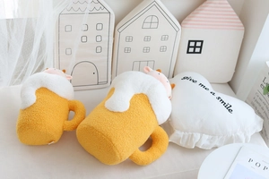Close-up of two beer mug plush pillows with soft yellow texture and white fluffy foam