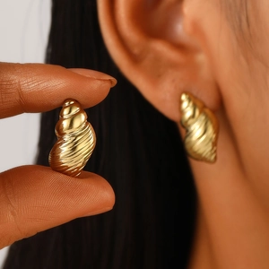 Detailed close-up of golden conch shell earrings with refined spiral texture and polished finish