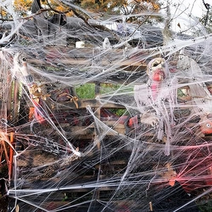 Realistic white spider web decoration draped over spooky props for Halloween party setup
