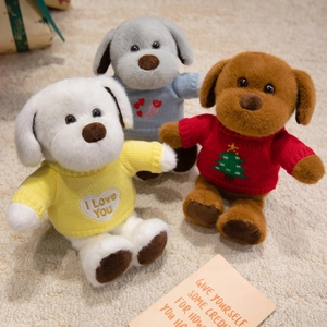 Trois peluches chiens en pulls tricotés colorés avec broderies dans un décor de cadeau