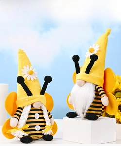 Close-up of yellow and black bee gnome plush dolls with white beard and braids on sky background
