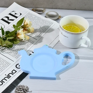 Detail view of light blue teapot silicone coaster with non-slip base in a tea setting
