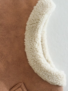 Detail of brown faux suede fabric and cream sherpa fleece lining on a vest