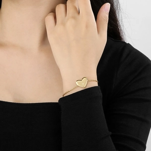 Détail d'un bracelet cœur doré avec petit diamant porté sur le poignet d'un modèle