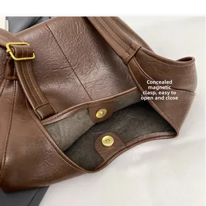 Nahaufnahme des goldenen Magnetverschlusses einer braunen Leder-Eimertasche