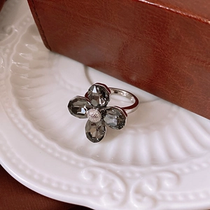 Detailed view of flower ring with smoky grey crystals and zircon core on ceramic tray