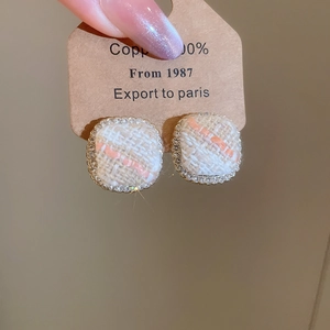 Detail of square tweed earrings with orange fabric and sparkling rhinestone border