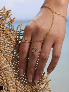 Détail d'une bague bracelet main dorée avec des trèfles sertis de zircons brillants