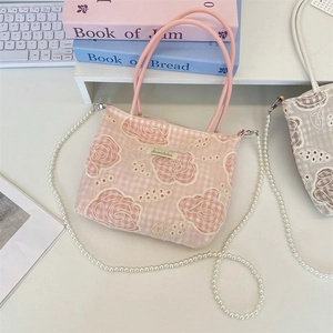 Détail de broderie florale en dentelle rose sur sac en toile avec chaîne de perles