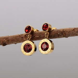 Elegant gold earrings with red round stones and Roman numerals on natural wood display