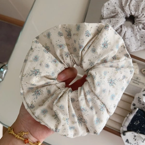 Detailed close-up of a floral cotton scrunchie in beige with light blue flower patterns