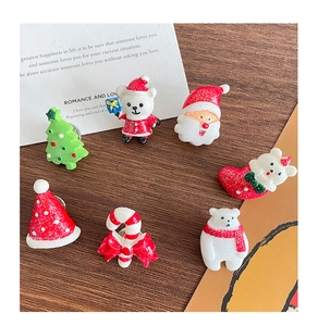 Glittery resin Christmas charms including trees and bears on a rustic wooden background