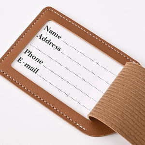 Detailed view of a brown PU leather luggage tag with white stitching and ID card window