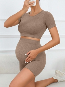 Detail of seamless ribbed maternity yoga set showing dark brown high-waist shorts and top