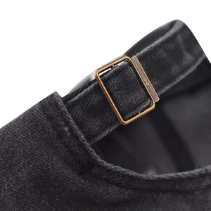 Close-up of the vintage bronze metal buckle on the black cotton baseball cap strap