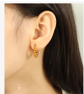 Close-up of golden beaded hoop earrings with high-gloss finish worn on model ear