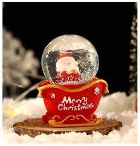 Close-up of Santa Claus snow globe with a red sleigh base and Merry Christmas text